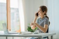 Happy smiling Asian woman relaxing using a smartphone to talk and laptop computer in bedroom at home. creative girl concept study Royalty Free Stock Photo