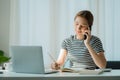 Happy smiling Asian woman relaxing using a smartphone to talk and laptop computer in bedroom at home. creative girl concept study Royalty Free Stock Photo