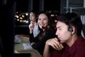 Happy smiling Asian woman work at call center service consultant working with teammate colleague overnight, night shift customer Royalty Free Stock Photo