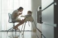 Happy Smiling Asian Young Mother enjoying feeding to her Little cute baby boy while sitting on high chair at home. Mom with first Royalty Free Stock Photo