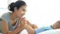 Asian Young mother gently kissing baby`s feet sleeping on bed Royalty Free Stock Photo