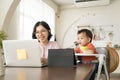 Happy smiling Asian Young mother and little son using laptop. Mom works from home office Royalty Free Stock Photo