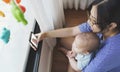 Happy Smiling Asian Young mother and newborn baby boy sitting on floor doing online video call with family on smartphone