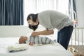 Happy Smiling Asian Young mother playing and dressing her little baby son on bed Royalty Free Stock Photo