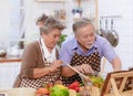 Happy & smiling attractive elderly cute Asian couple in love enjoying cooking healthy salad in kitchen at home together. Happiness Royalty Free Stock Photo