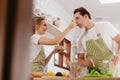 Happy & smiling attractive young cute caucasian couple in love enjoying cooking healthy salad in kitchen at home together. Royalty Free Stock Photo