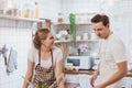 Happy & smiling attractive young cute caucasian couple in love enjoying cooking healthy salad in kitchen at home together. Royalty Free Stock Photo