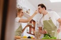 Happy & smiling attractive young cute caucasian couple in love enjoying cooking healthy salad in kitchen at home together. Royalty Free Stock Photo