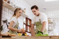 Happy & smiling attractive young cute caucasian couple in love enjoying cooking healthy salad in kitchen at home together. Royalty Free Stock Photo