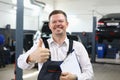 Happy smiling auto mechanic showing thumbs up gesture in workshop Royalty Free Stock Photo
