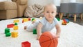 Happy smiling baby boy crawling on carpet and playing with basketball ball. Concept of children development, sports Royalty Free Stock Photo