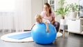 Happy smiling baby boy doing exercises and playing with big blue fitness ball at home Royalty Free Stock Photo