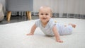 Happy smiling baby boy lying on soft carpet in living room. Concept of child development, happy childhood and fun at Royalty Free Stock Photo