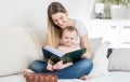 Happy smiling baby boy reading big old book on bed with mother Royalty Free Stock Photo