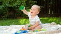 Happy smiling baby boy sitting on grass at park and playing with toy blocks and bricks Royalty Free Stock Photo