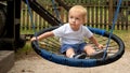 Happy smiling baby boy swinging in rope nest swing on playground. Kids playing outdoors, children having fun, summer vacation Royalty Free Stock Photo