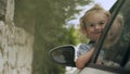 Happy smiling baby girl looking out of the driver side window of a car Royalty Free Stock Photo