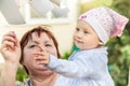 Happy smiling baby girl playing with cheerful grandmother outdoors. Together they are catching flying paper lists. Royalty Free Stock Photo