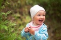 Happy smiling baby girl wearing light-blue jacket and white hat standing outside Royalty Free Stock Photo