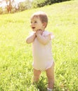 Happy smiling baby standing on grass in sunny summer