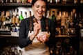 Happy smiling barman girl crushing a piece of ice for making a c