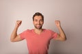 Happy smiling bearded man in fashionable pink t-shirt with copy space with arms raised up Royalty Free Stock Photo
