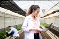 Happy smiling beautiful Asian botanist scientist woman in lab coat holding laptop computer, female biological researcher working