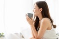 Happy smiling beautiful Asian woman enjoying first morning and smelling aroma of cup of coffee tea in her bedroom.Enjoying free Royalty Free Stock Photo