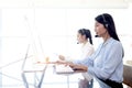 Happy smiling beautiful Asian woman with headphones working with desktop computer at call center service desk, female agent with Royalty Free Stock Photo