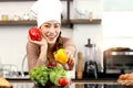 Happy smiling beautiful Asian woman wearing apron and chef hat holding bell peppers at kitchen with fresh vegetables salad food Royalty Free Stock Photo
