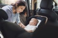 Happy Smiling Beautiful Asian young mother putting her baby son into car seat and fasten seat belts in the car Royalty Free Stock Photo