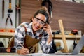 Happy smiling beautiful carpenter woman wearing safety glasses goggles and apron taking to customer by using mobile phone, female Royalty Free Stock Photo