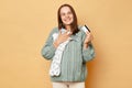 Smiling beautiful future mother young pregnant woman with baby bodysuits isolated over beige background embracing kid's Royalty Free Stock Photo