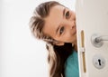 Happy smiling beautiful girl behind door at home Royalty Free Stock Photo