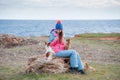 Happy smiling beautiful girl in hat track suit sitting on stone with two dogs