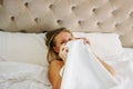 Happy smiling beautiful long fair hair woman in underwear closing face sitting on bed in bright rich interior Royalty Free Stock Photo