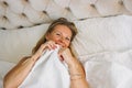 Happy smiling beautiful long fair hair woman in underwear closing face sitting on bed in bright rich interior Royalty Free Stock Photo