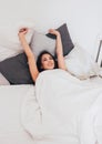 Happy smiling beautiful long hair asian girl young woman lying down in bed, cozy morning Royalty Free Stock Photo