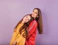 Happy smiling beautiful mother and cute playful daughter hugging in fashion trendy hoodie together on purple studio background