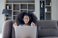 Happy smiling beautiful teenage girl with curly hair wearing headphones, using laptop computer for practicing to sing song while Royalty Free Stock Photo