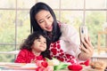 Happy smiling beautiful young Asian mom holding mobile phone taking selfie with her little adorable child daughter girl, mother Royalty Free Stock Photo