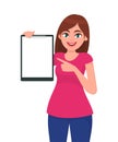 Happy smiling beautiful young woman holding / showing a blank clipboard and pointing towards. Royalty Free Stock Photo