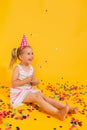 Happy smiling birthday child girl in pink cup surrounded by flying confetti on colored yellow background . Celebration Royalty Free Stock Photo