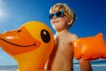 Happy smiling blond boy with inflatable yellow duck buoy Royalty Free Stock Photo