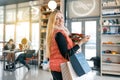 Happy smiling blonde in coffee shop with shopping bags and red poinsettia christmas flower. Winter portrait, girl in woolen scarf Royalty Free Stock Photo