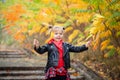 Happy smiling blonde girl holding yellow red leaves in sunny autumn park Royalty Free Stock Photo