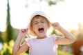 Happy and smiling blonde toddler girl in pink dress and hat. Happiness. Outdoor. Summer, sunset light