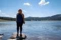 Happy smiling blonde woman stands on a rock in Meadowlark Lake in Wyoming, holding a phone