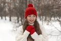 Happy smiling blue-eyed young woman in knitted red hat and mittens and woolen sweater in winter forest. Female knitwear Royalty Free Stock Photo