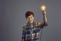 Happy smiling boy child holding glowing lightbulb lamp above head headshot